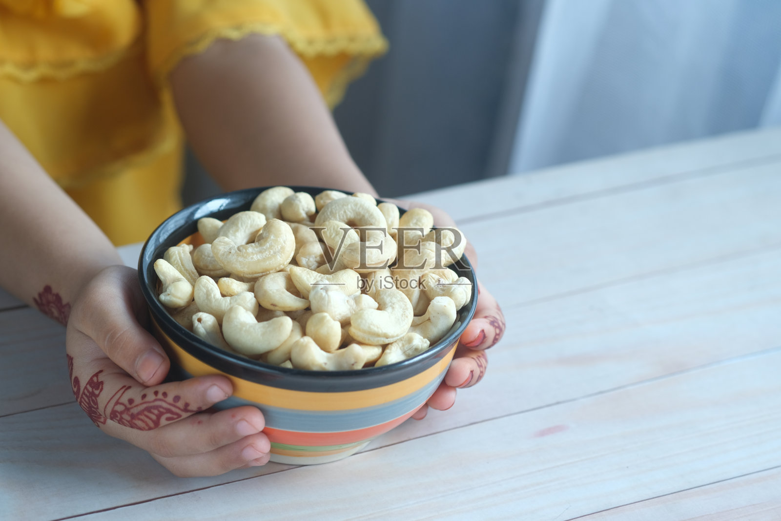 孩子手捧一碗腰果照片摄影图片