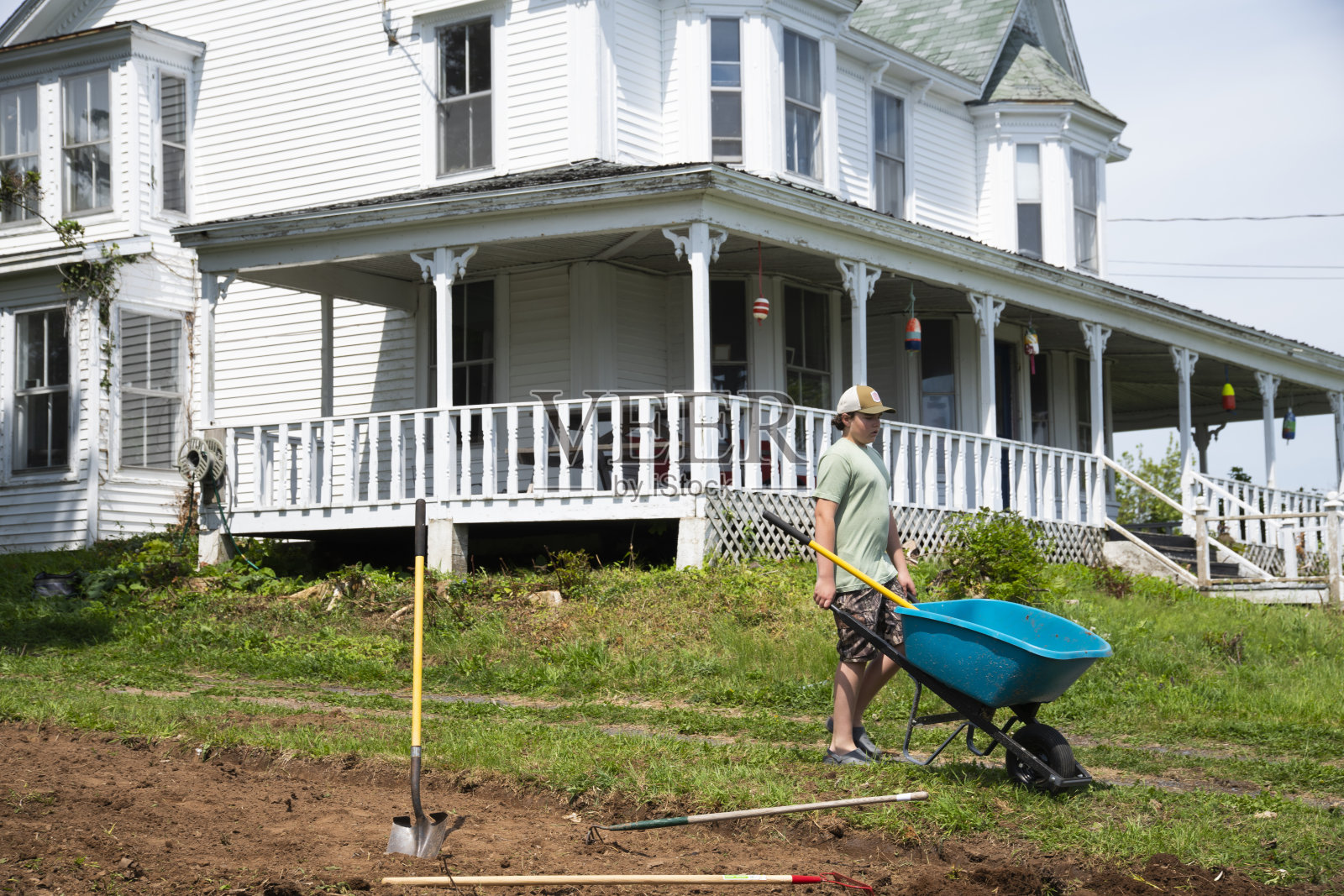 一个在菜园里挖土的少年照片摄影图片