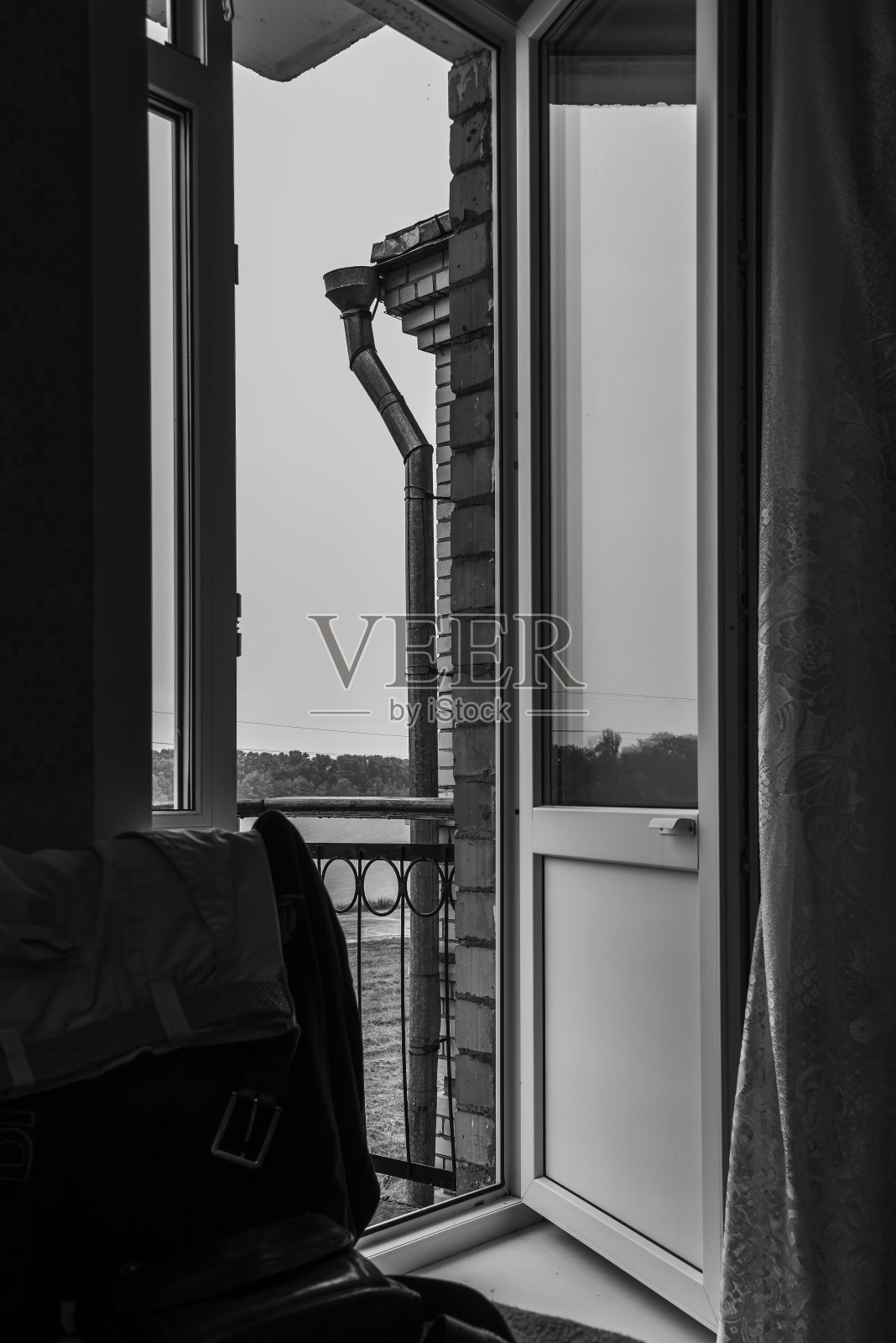 从房间到开放式阳台，后面是阳台栏杆、水管、多云的天空、森林和河流。照片摄影图片