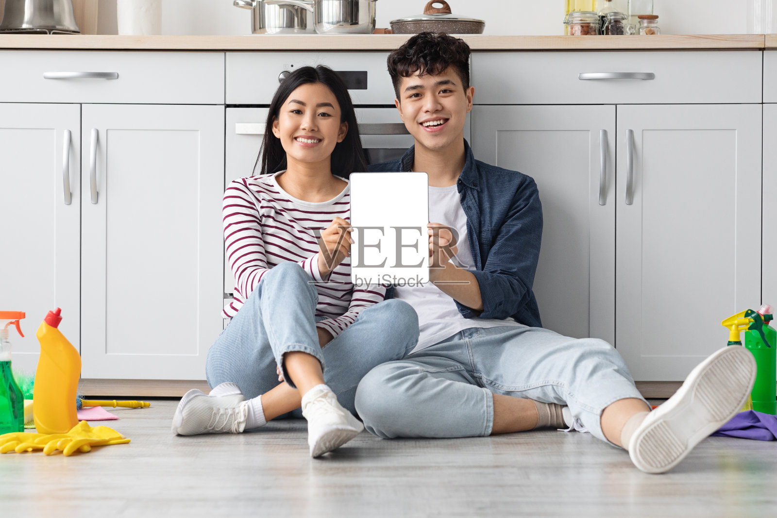 一对亚洲夫妇坐在厨房的地板上，展示着数码平板电脑照片摄影图片