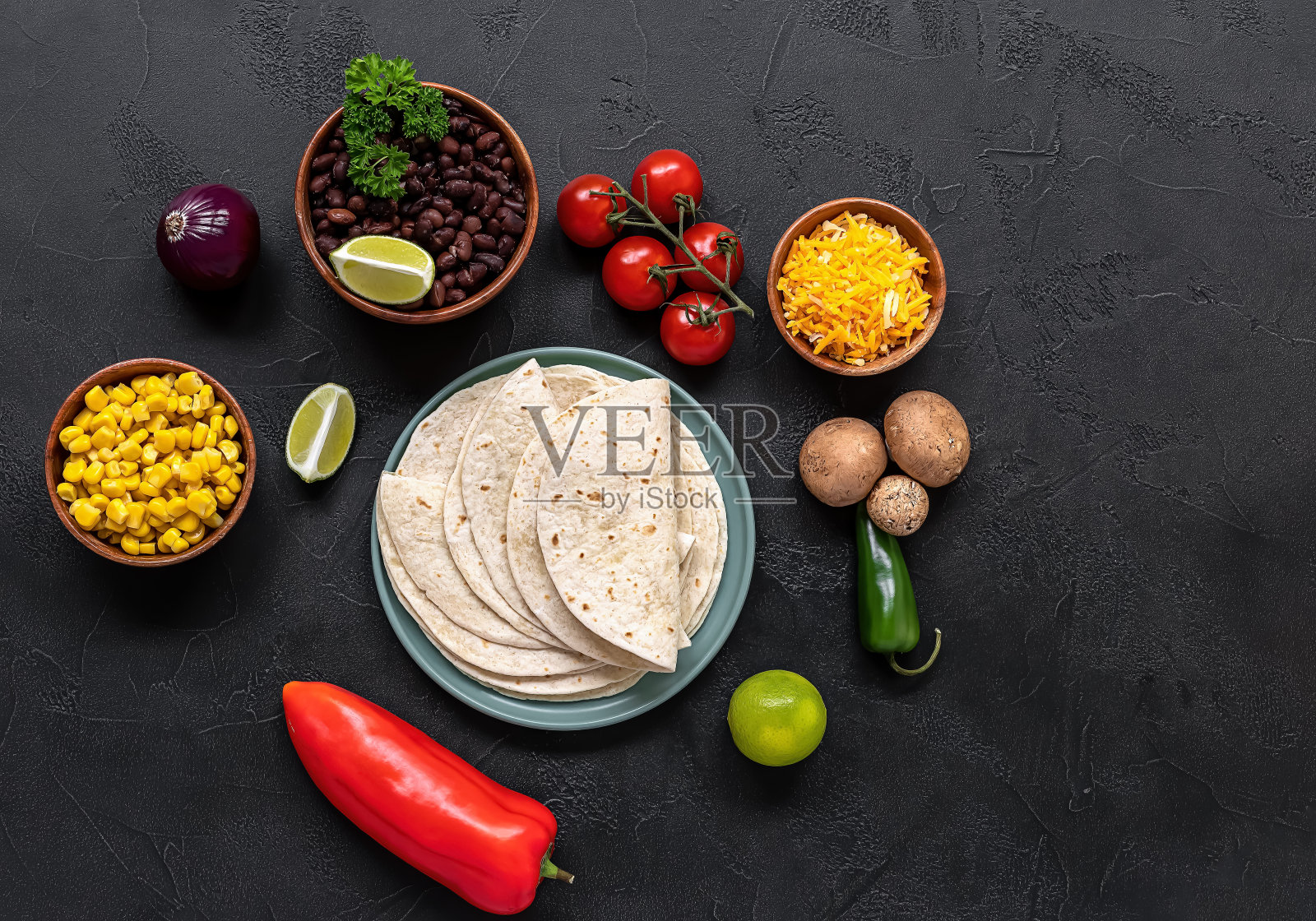 准备用蘑菇、豆子、辣椒、玉米和奶酪烹制素食玉米饼。照片摄影图片