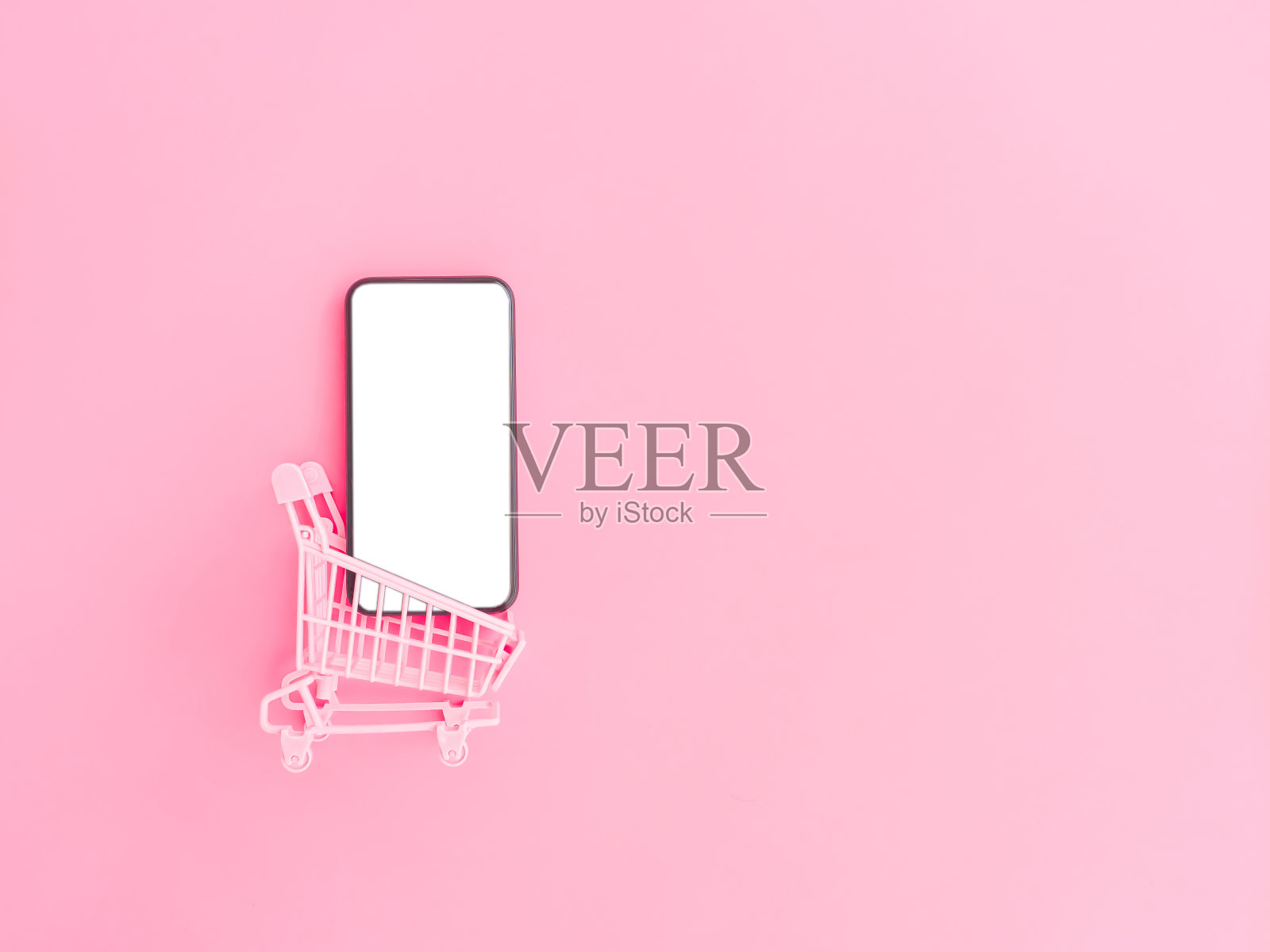 购物和网上支付概念从粉色钱包，信用卡，购物车和粉色粉彩背景上的空白智能手机。照片摄影图片