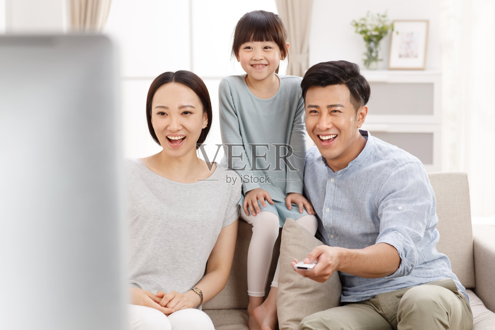 幸福的一家三口在客厅看电视照片摄影图片