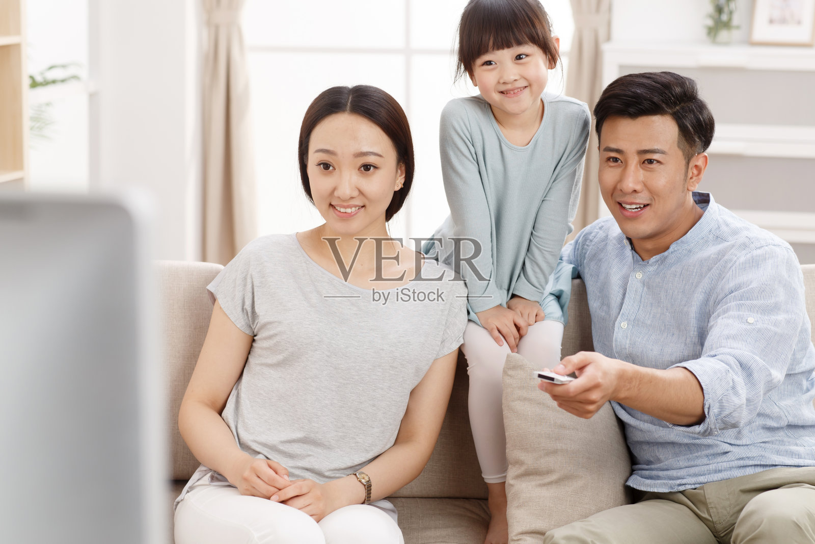 幸福的一家三口在客厅看电视照片摄影图片