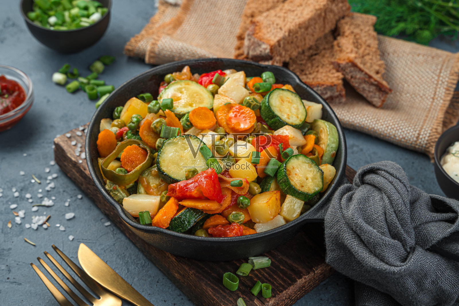 灰蓝色背景的煎锅里有烤好的蔬菜照片摄影图片