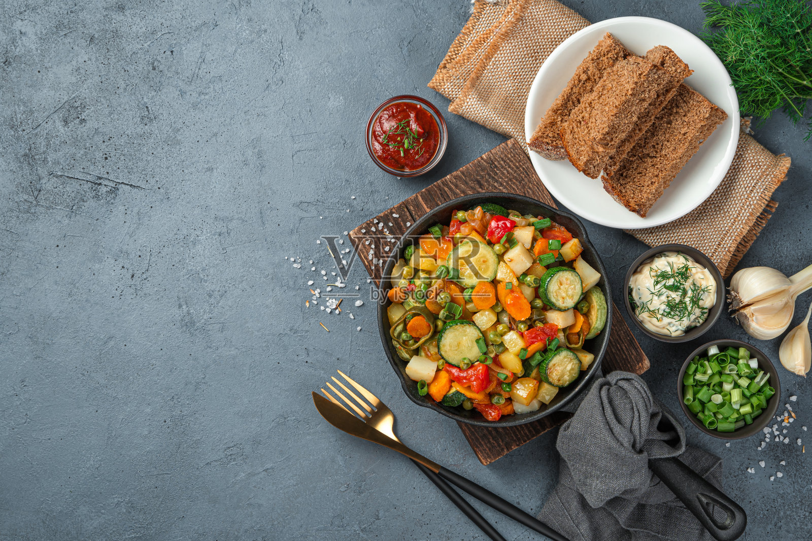 午餐有蔬菜炖菜，黑麦面包，酱汁和香草在深灰色的背景照片摄影图片