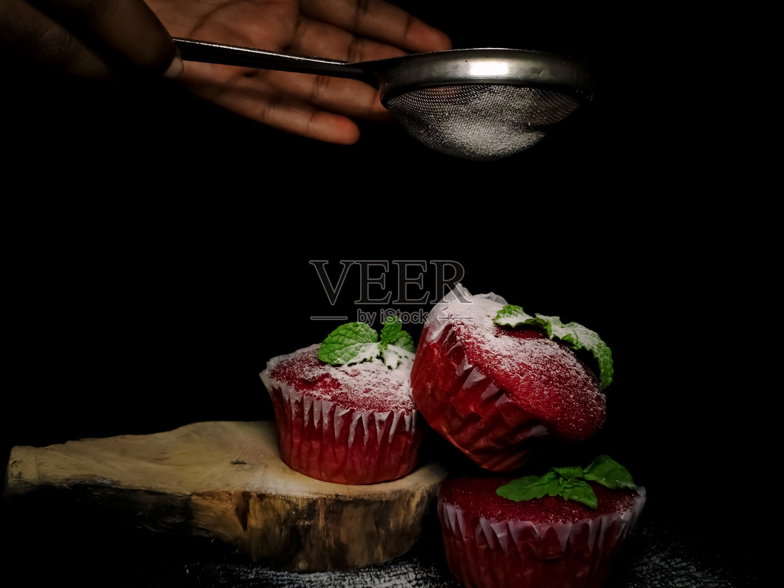 特写美味的红丝绒纸杯蛋糕或松饼与糖霜和薄荷在顶部孤立在一个黑色乡村背景。照片摄影图片