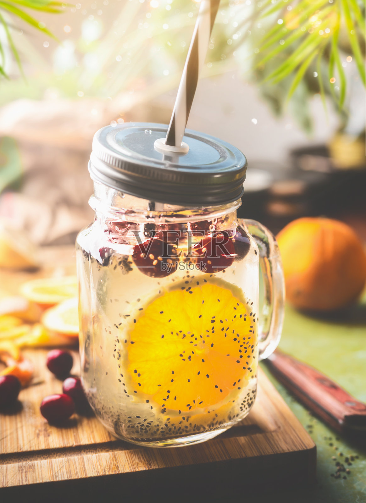 奇亚籽排毒水。健康的饮料与橙水果片，柠檬汁和蔓越莓在玻璃罐和饮用吸管照片摄影图片