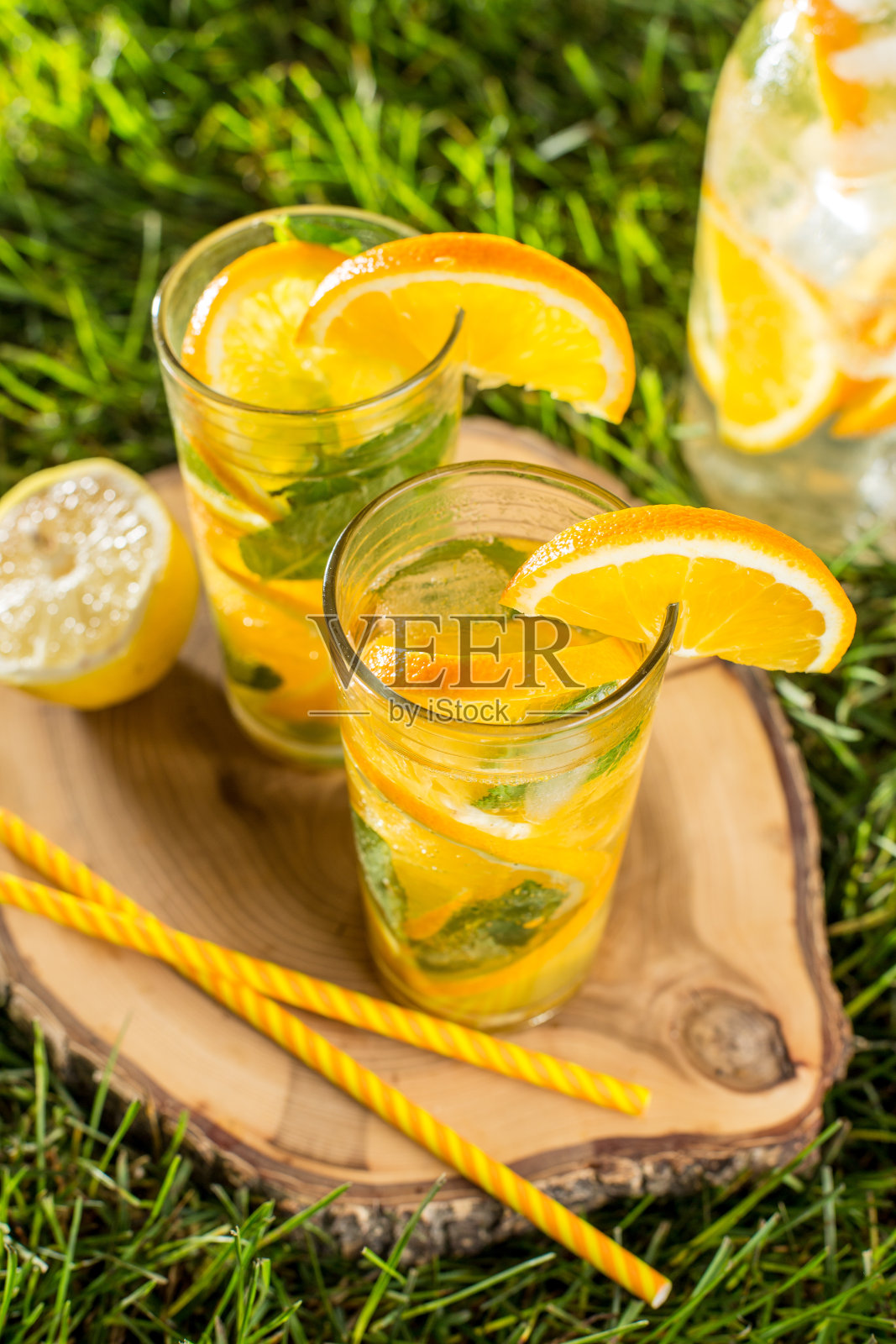 冷饮柠檬水与橙和薄荷高脚杯在绿色草地草坪木制背景照片摄影图片