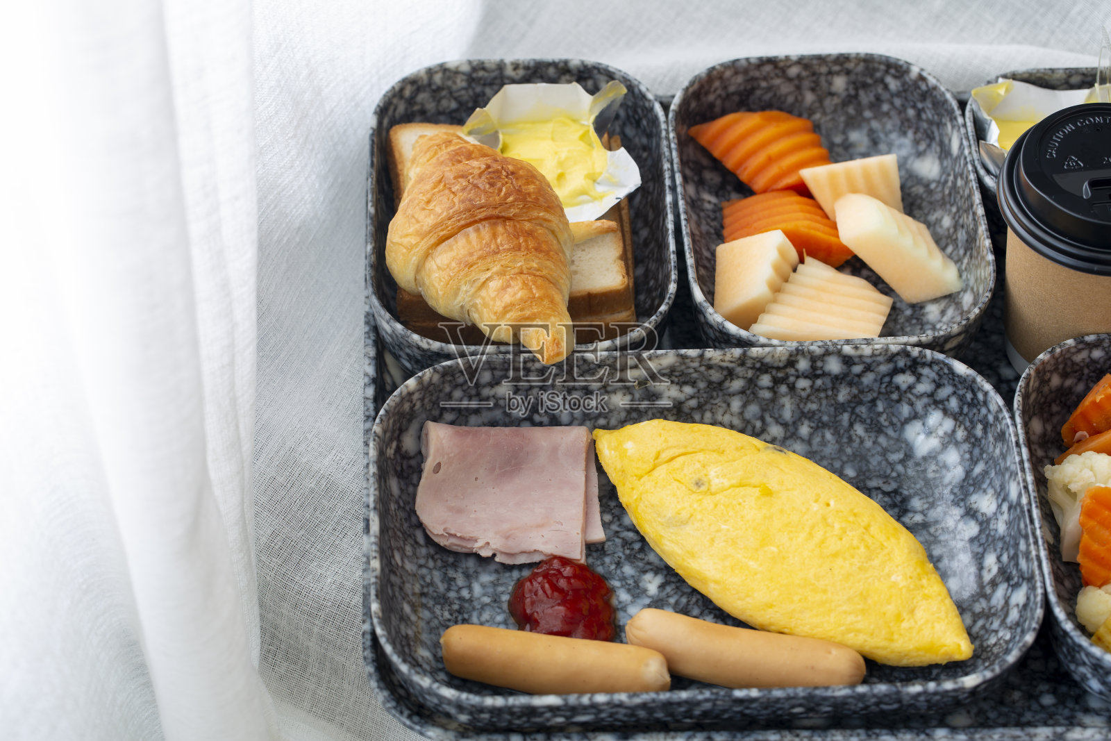 早餐包括羊角面包、蔬菜、鸡蛋、火腿、香肠、新鲜水果和咖啡照片摄影图片