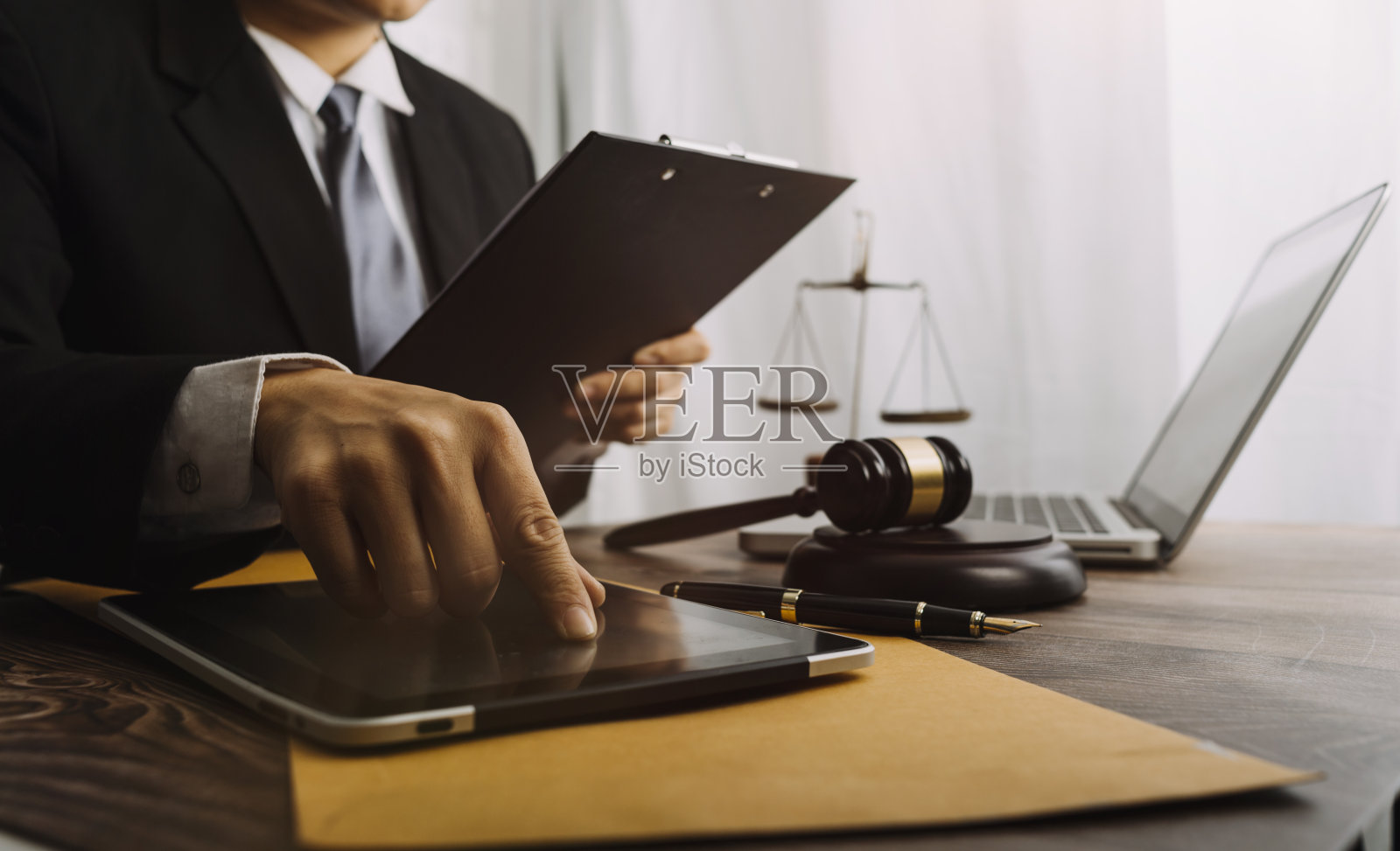 正义与法律观念。男法官在法庭上用木槌工作，电脑和对接键盘，眼镜，在晨光下放在桌子上照片摄影图片