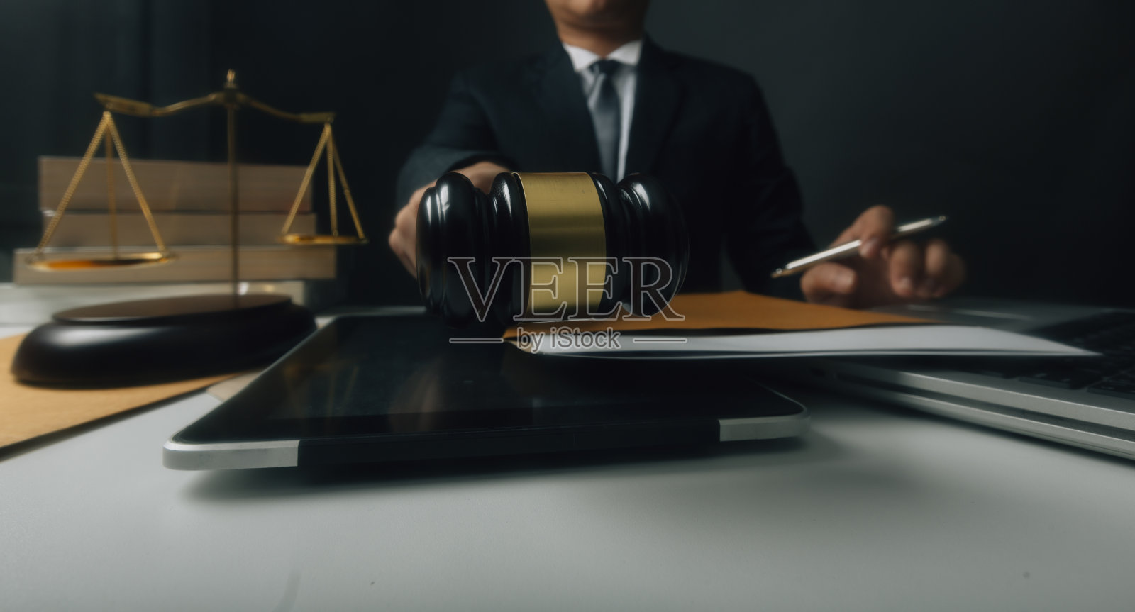 正义与法律观念。男法官在法庭上用木槌工作，电脑和对接键盘，眼镜，在晨光下放在桌子上照片摄影图片