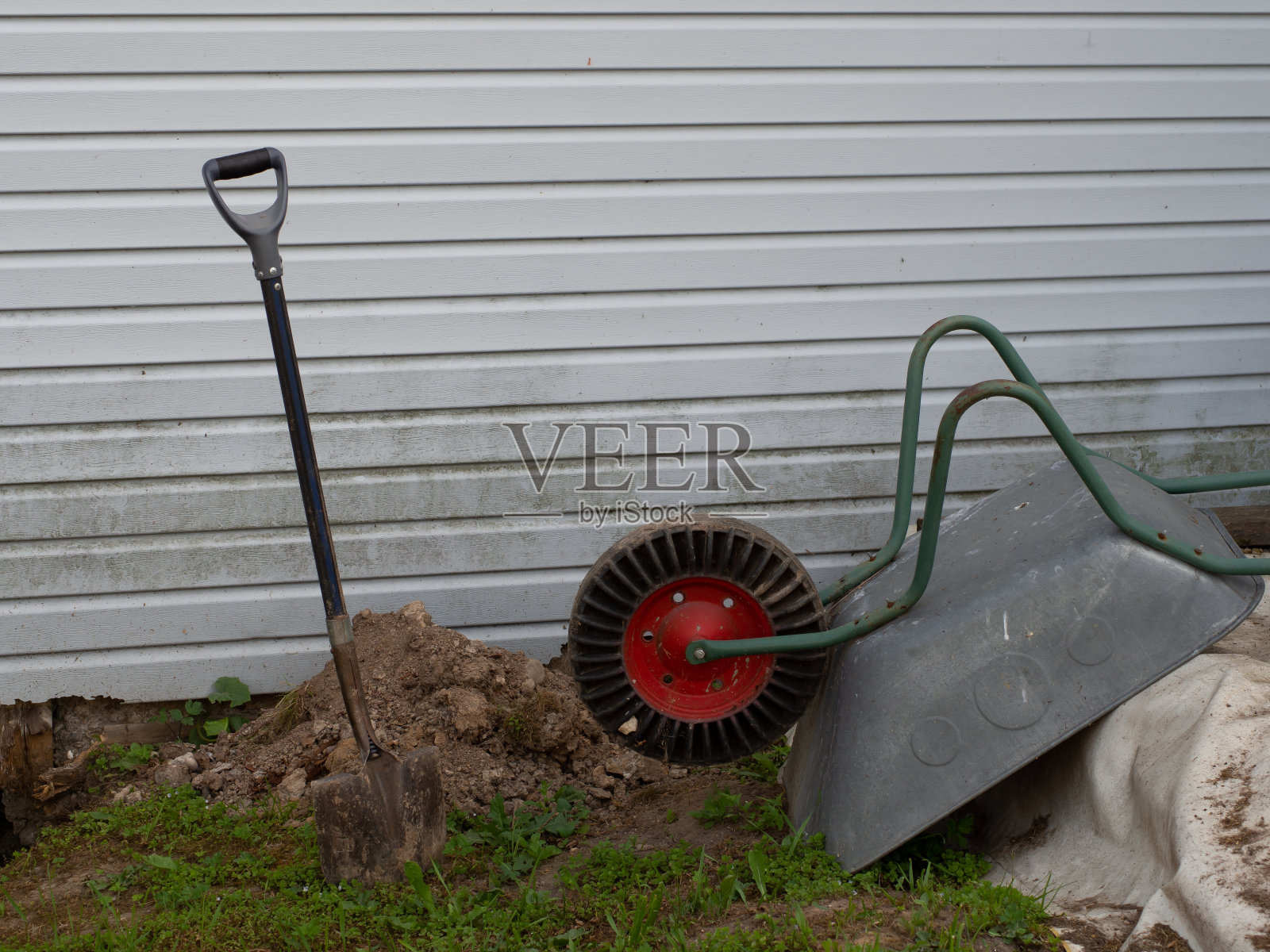 倒立的独轮车和铲子在地上象征着午餐休息或工作日的结束照片摄影图片