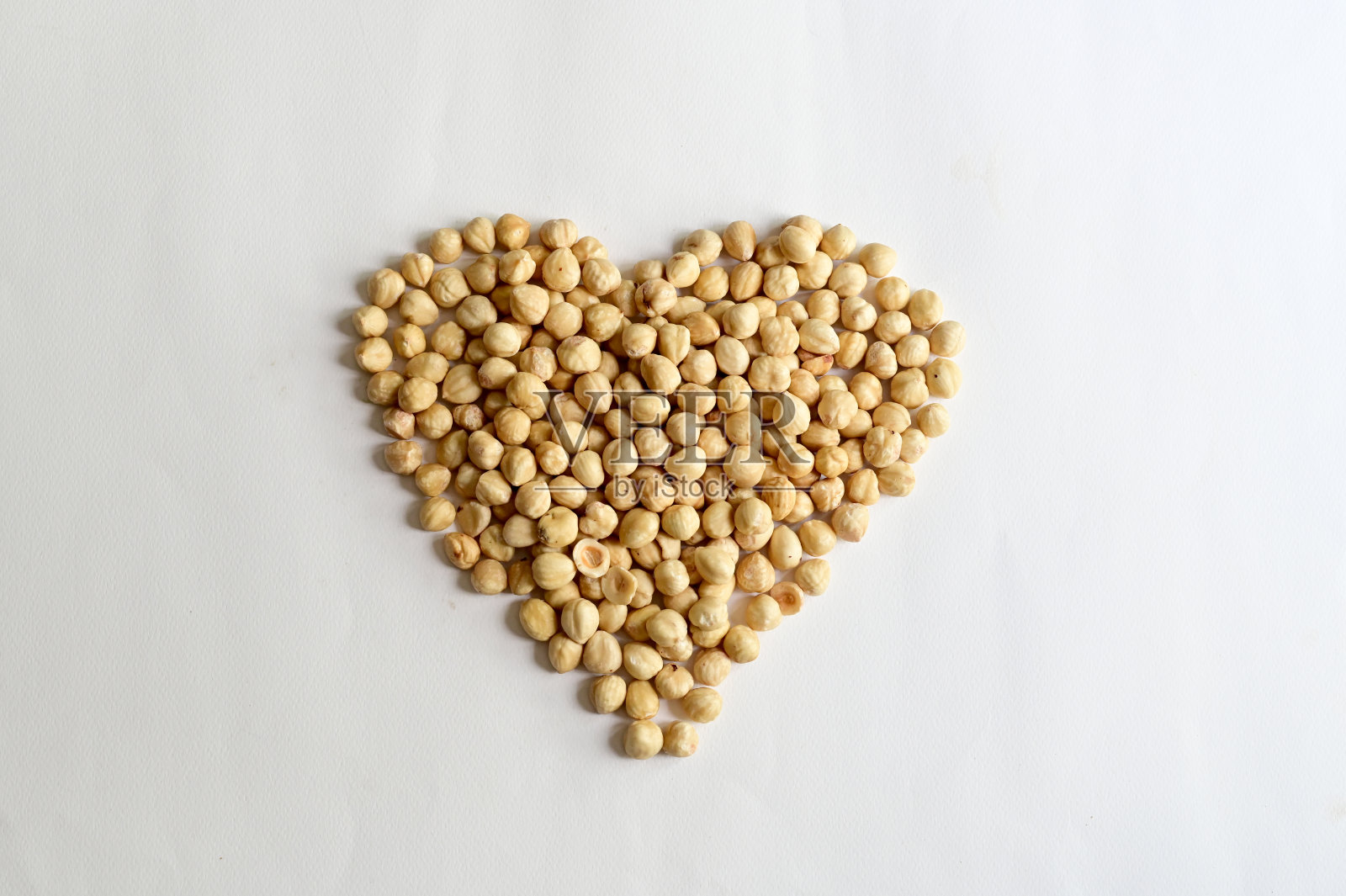 在白色背景上孤立的心形榛子，健康食品概念。照片摄影图片