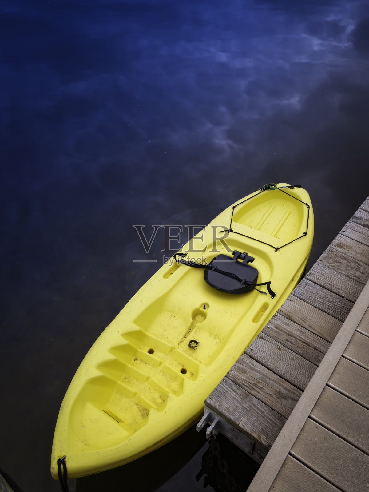 黄色皮艇斜系在私人码头的木制码头上，俯视图。照片摄影图片