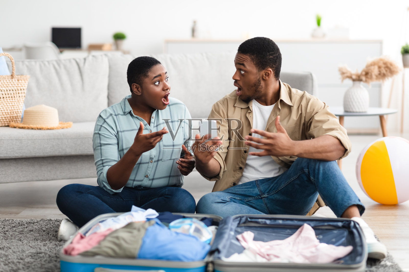 震惊的黑人游客夫妇拿着手机，坐在室内行李箱附近照片摄影图片