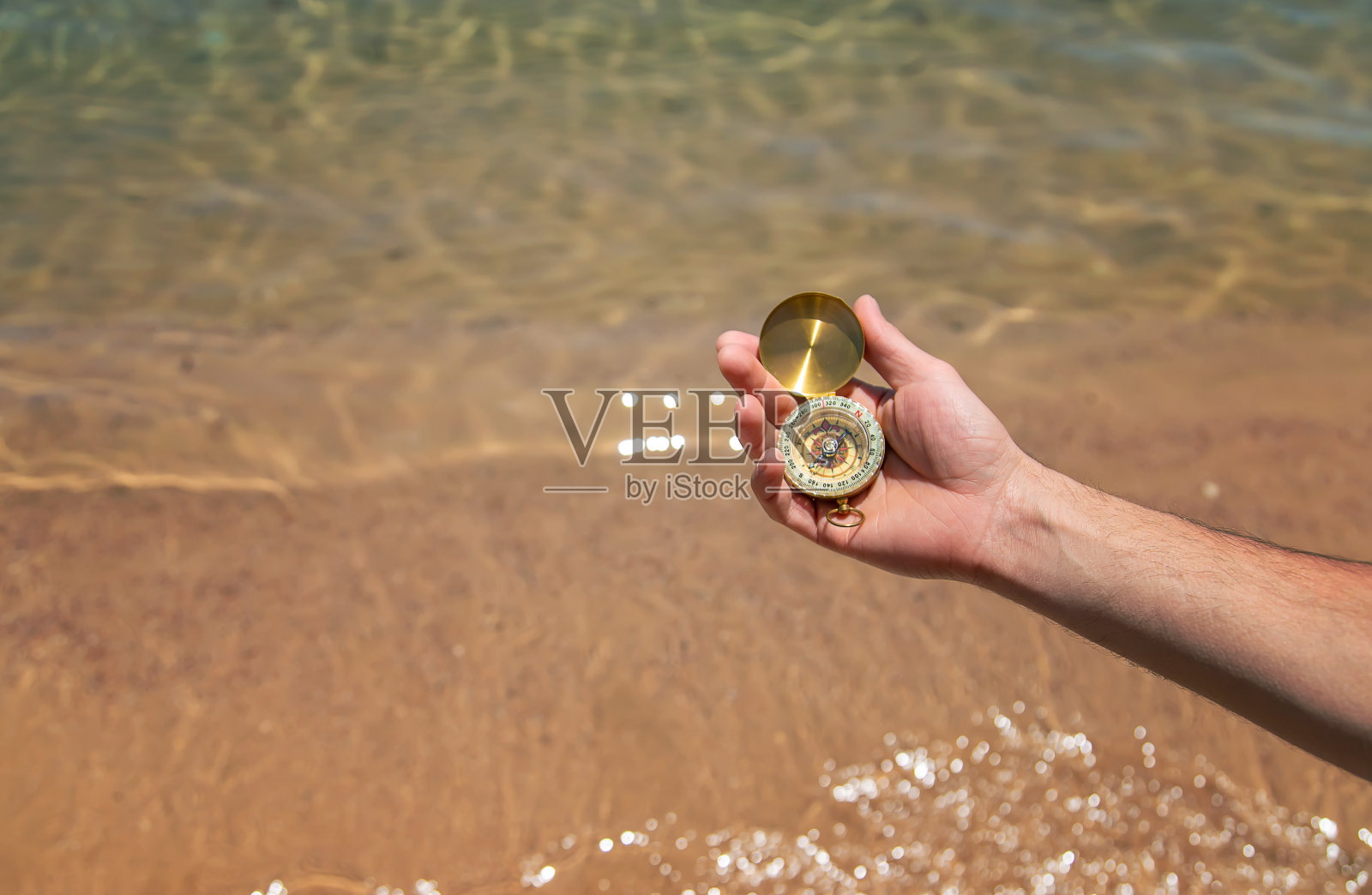手拿指南针，背景是大海。有选择性的重点。照片摄影图片