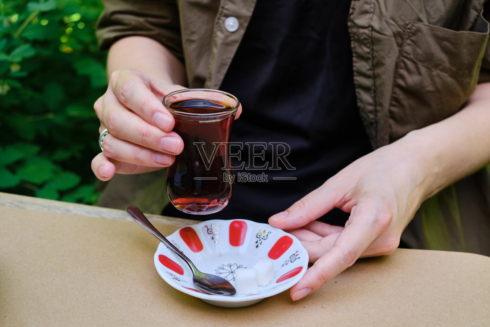 女孩在餐厅的夏季露台上喝土耳其茶，用传统玻璃杯盛着，一杯芳香的热茶配一块方糖，享受片刻，休息一下照片摄影图片