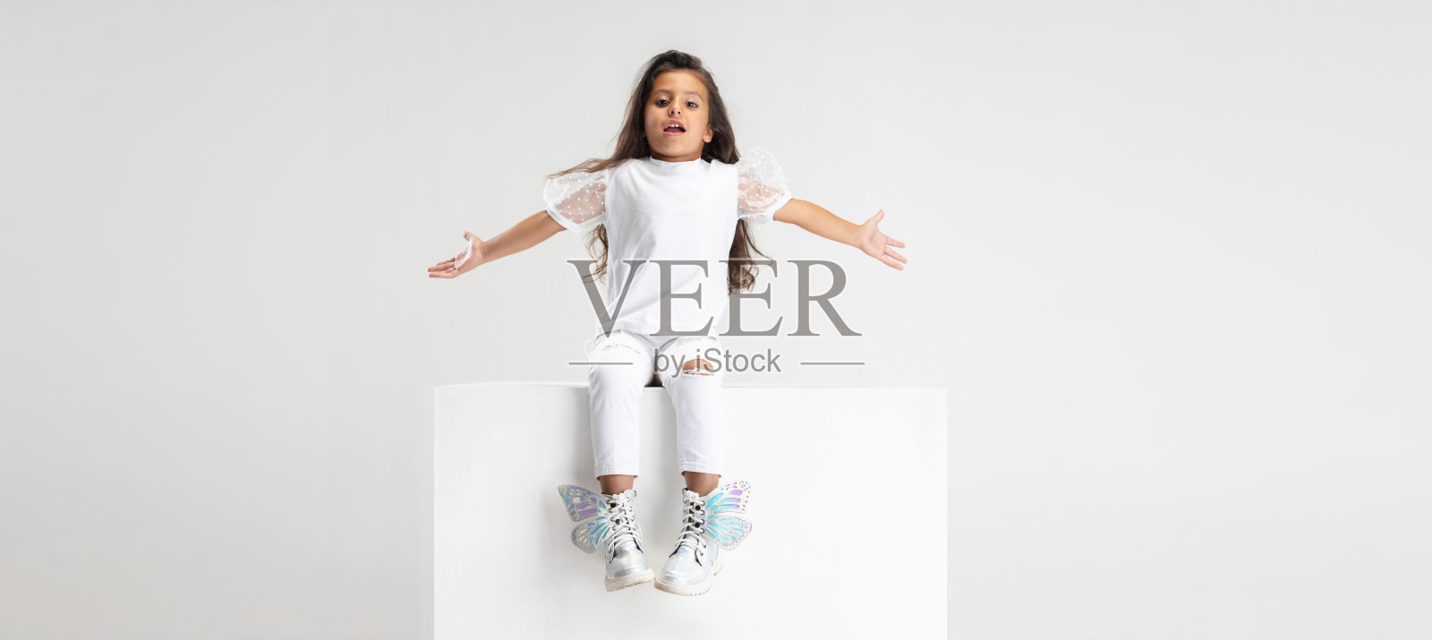 小可爱的白人女孩坐在大盒子上的肖像，在白色的工作室背景上孤立。摩天观景轮照片摄影图片