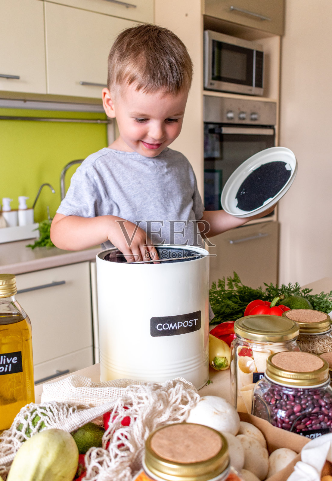 一个小男孩把食物垃圾放在堆肥箱里。垃圾分类。照片摄影图片