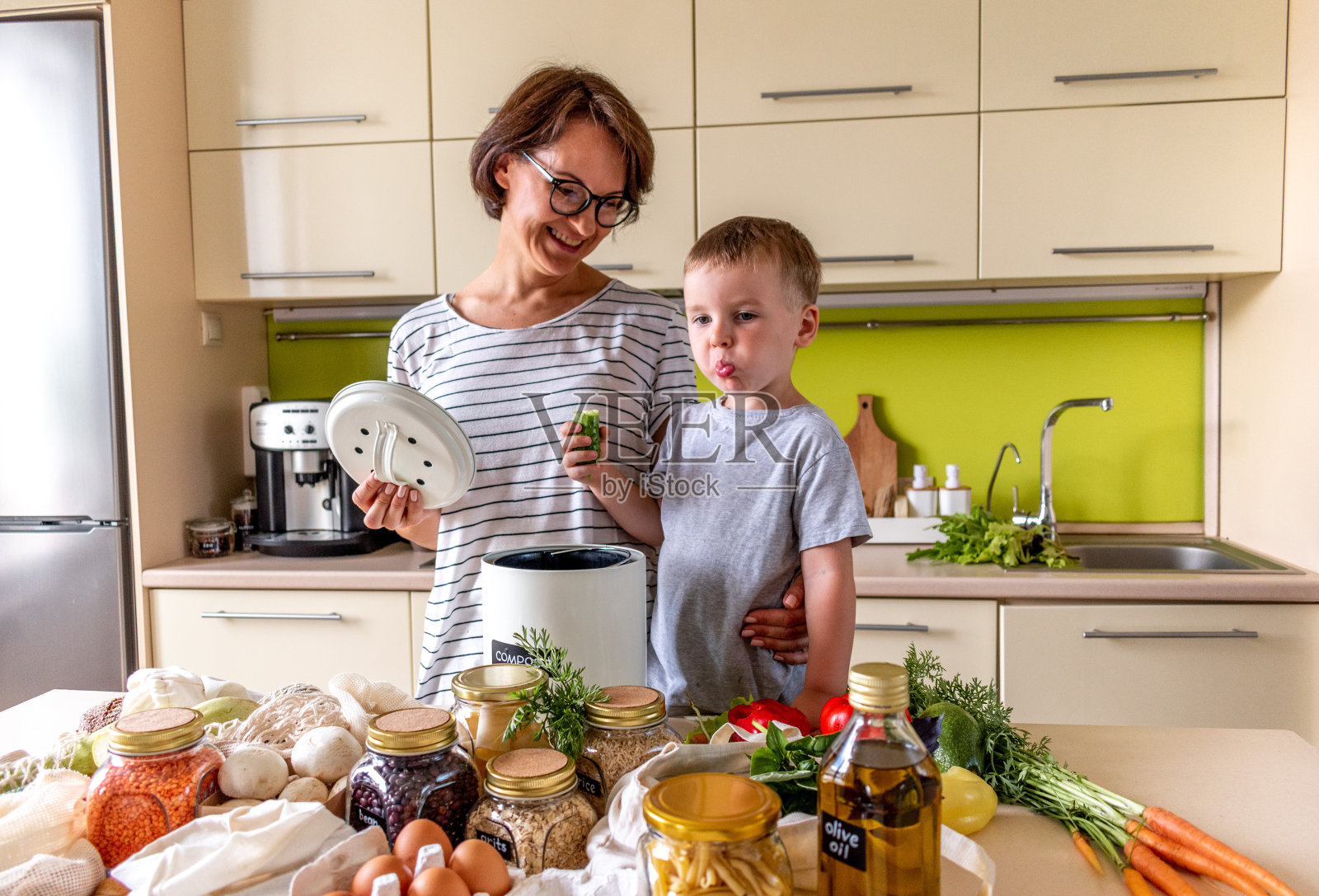 男孩和妈妈把食物垃圾放进堆肥箱。副本的空间。垃圾分类。照片摄影图片