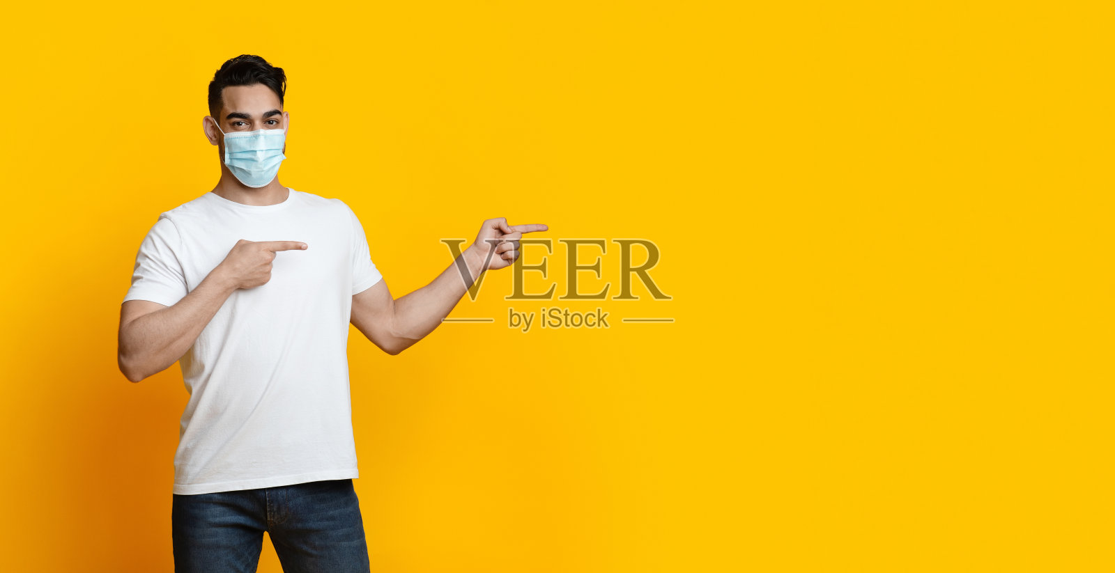 戴口罩的阿拉伯男子指向空白区域照片摄影图片