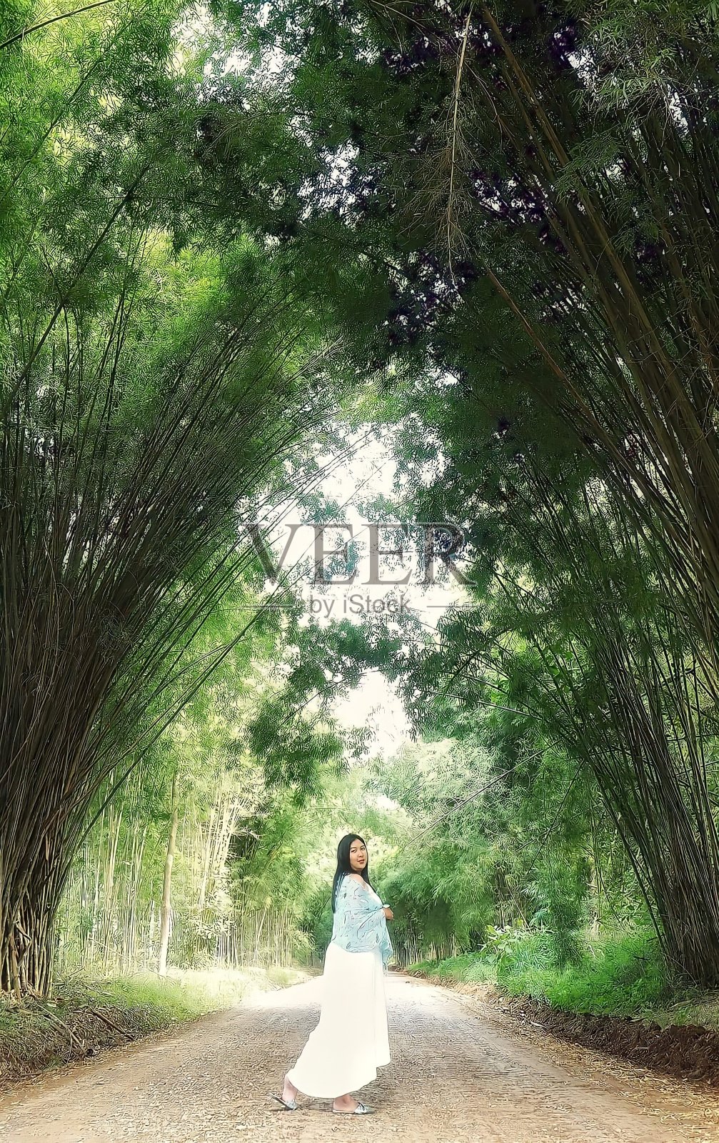 一个女人在一条竹制隧道下的砾石路上照片摄影图片