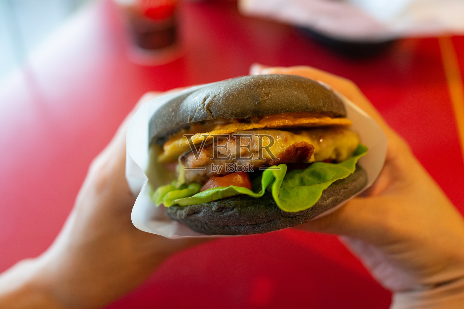 特写成年人的手拿着一个汉堡，准备吃。照片摄影图片