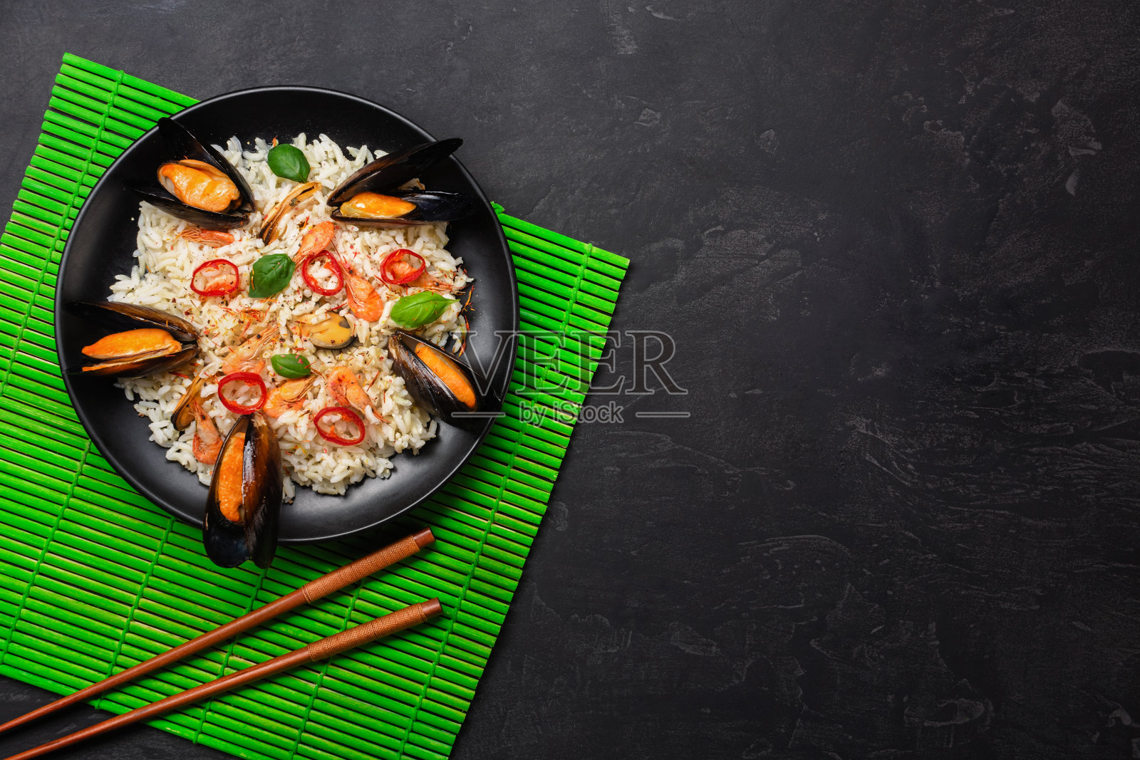 青竹席石桌，黑盘子，虾仁和罗勒炒饭照片摄影图片