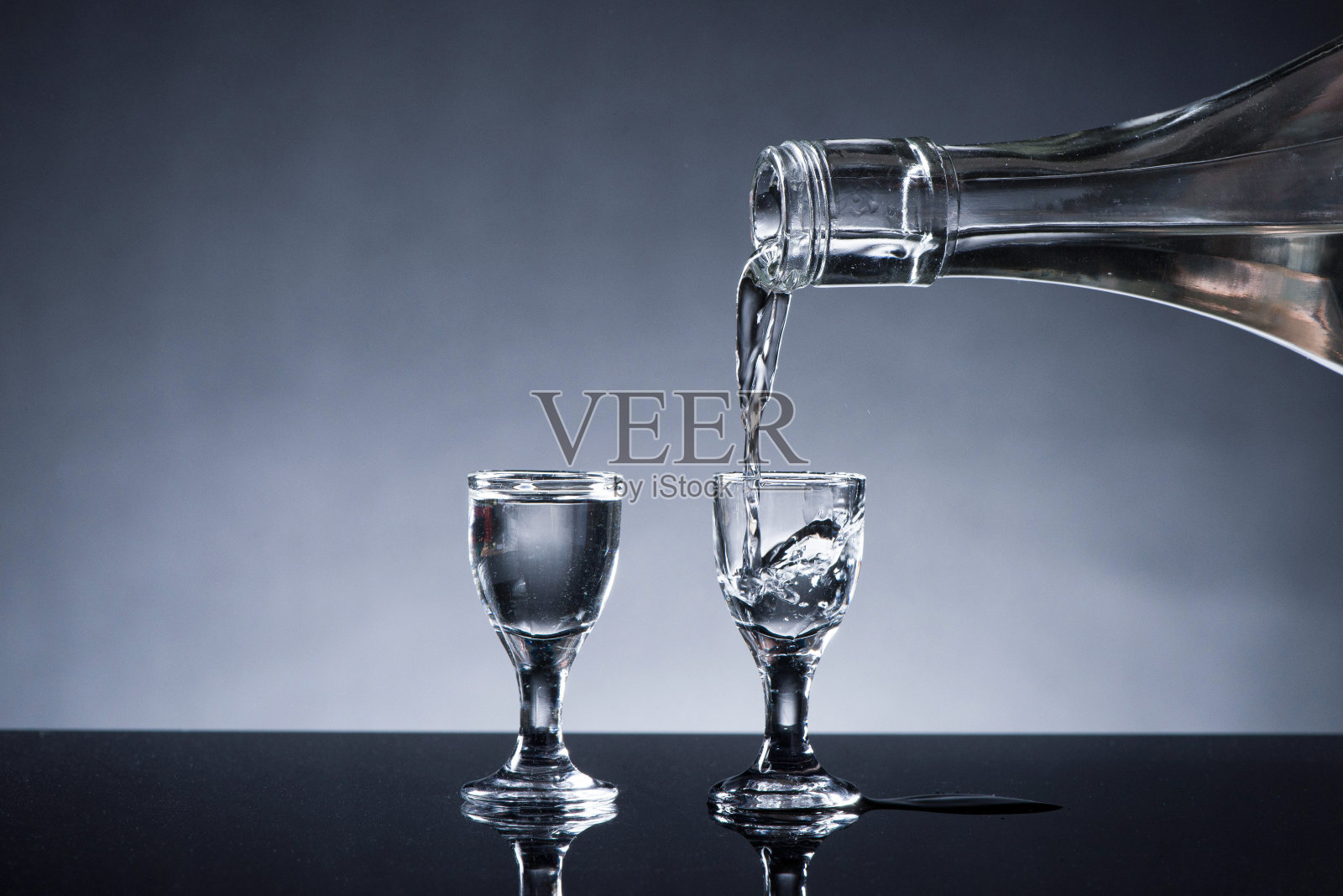 烈酒或烈性酒是从一个瓶子的背景倒进玻璃杯照片摄影图片