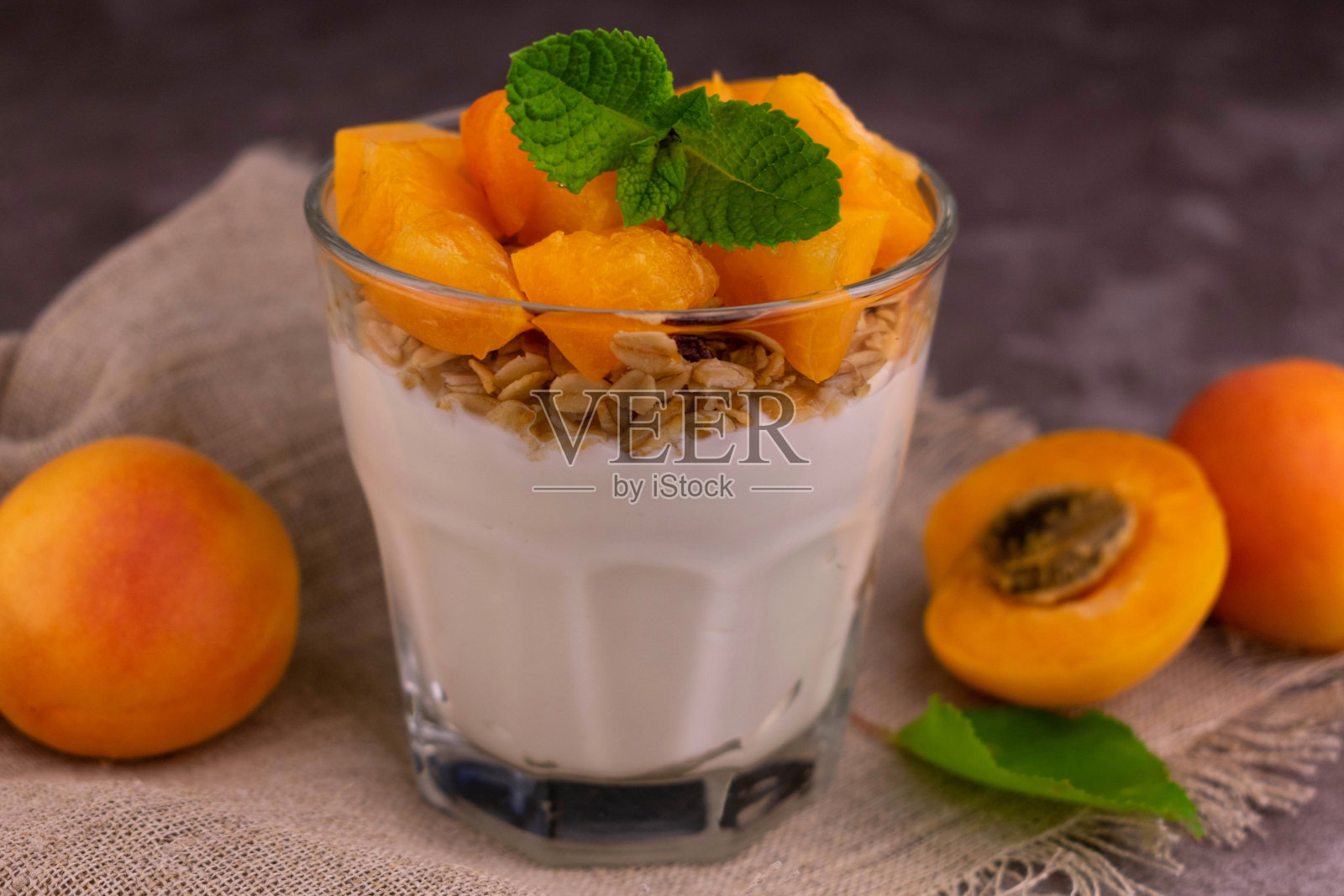 在灰色背景下的一杯杏仁酸奶和什锦麦片。特写镜头。照片摄影图片