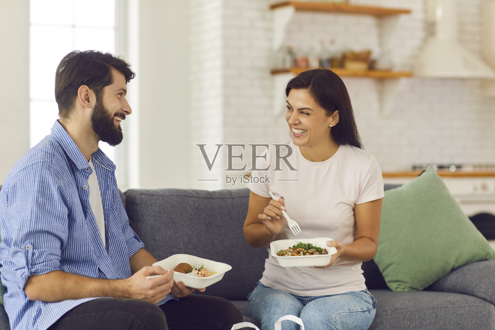 一对年轻的夫妇坐在家里吃着健康的盒装食品照片摄影图片