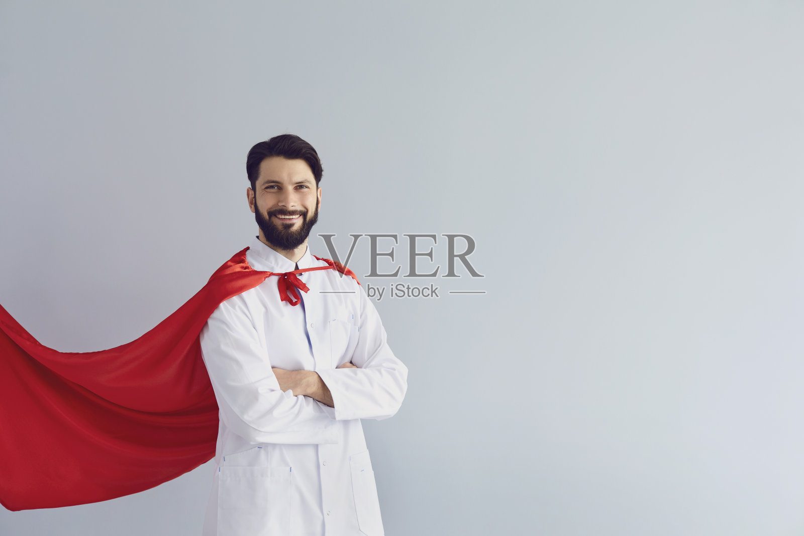 博士是个超级英雄。身穿超级英雄服装的医生在灰色背景下微笑。照片摄影图片