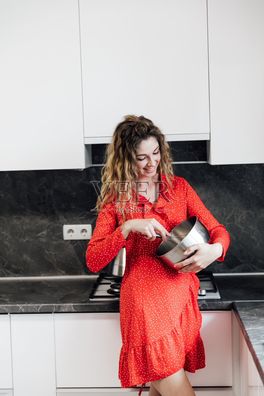 穿着红裙子的漂亮女人在厨房里准备甜点照片摄影图片