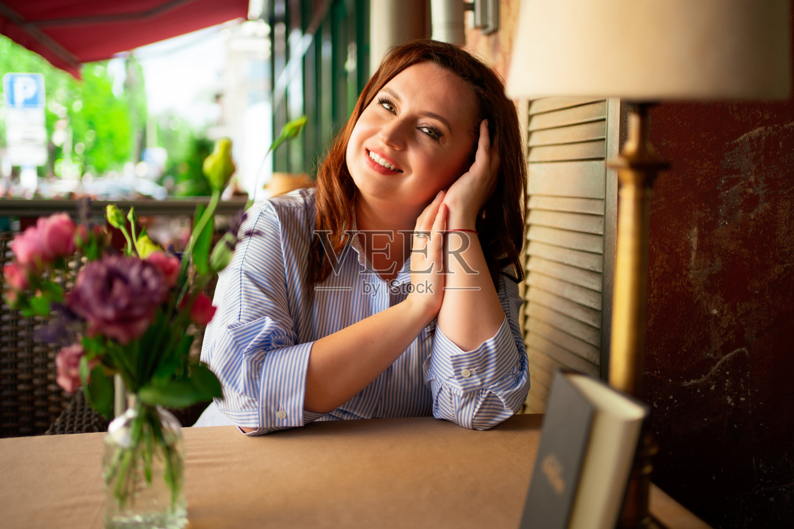 一个迷人的女人穿着蓝色长裙，长发坐在咖啡桌旁照片摄影图片