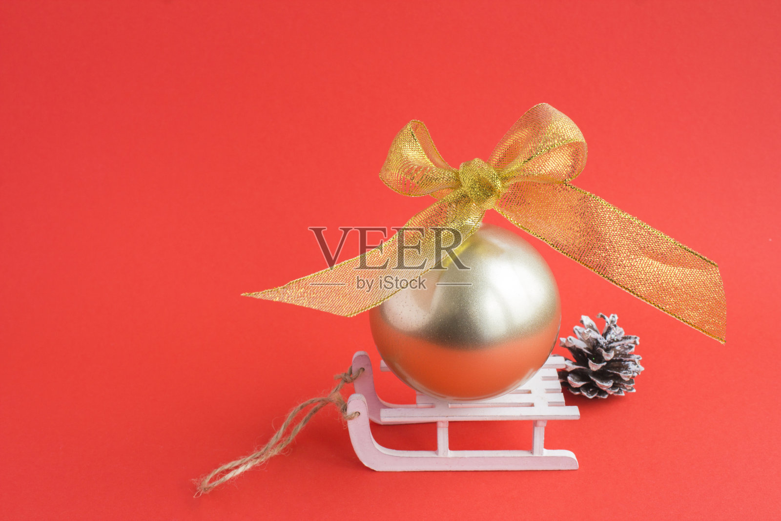 红色背景上白色玩具雪橇上的金球圣诞作文照片摄影图片