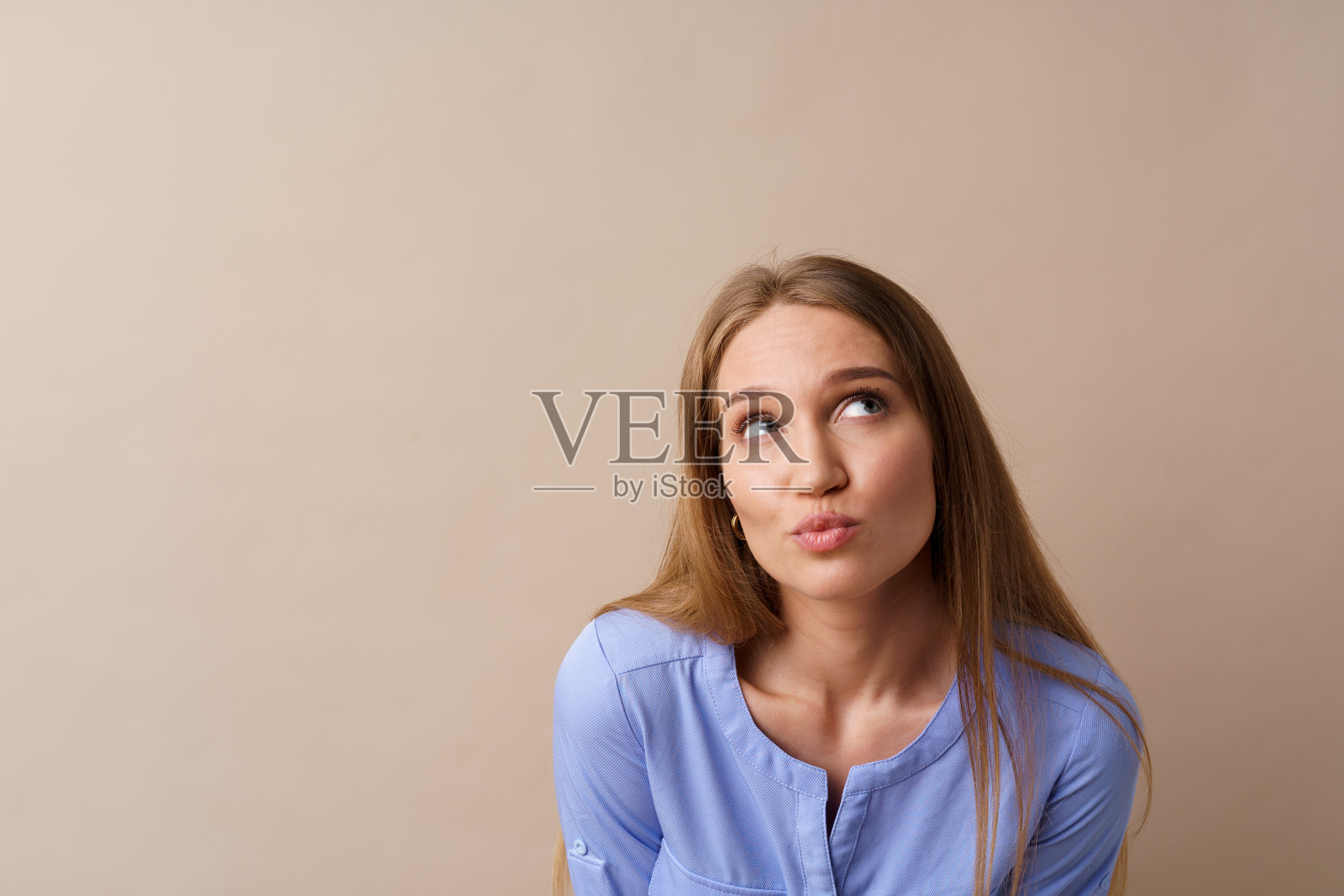 沉思的年轻女商人在米色的背景下思考一些想法照片摄影图片