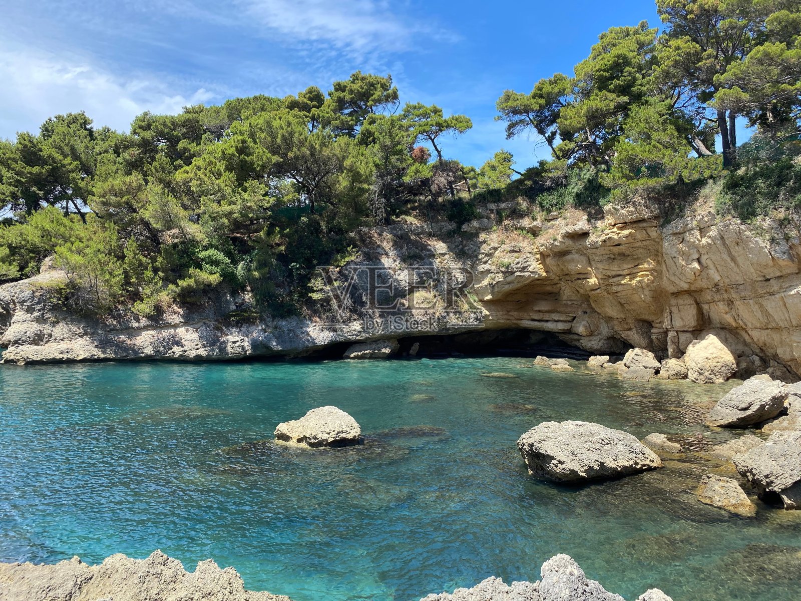 夏天阳光明媚的绿松石海泻湖。美丽的岩石海滩之间的松树地中海海岸。平静透明的海水。幽静的地方，快乐放松的假期。照片摄影图片