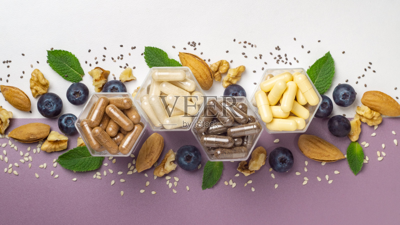 各种含有膳食补充剂或维生素的胶囊，在蜂房形式的罐子和新鲜的蓝莓和坚果照片摄影图片
