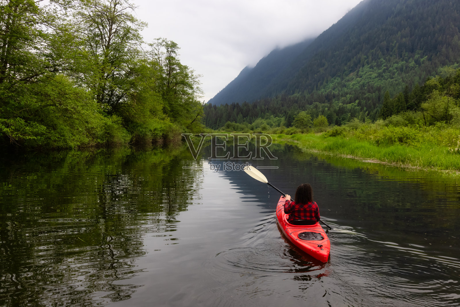在红色皮划艇上划皮划艇的白人女性照片摄影图片