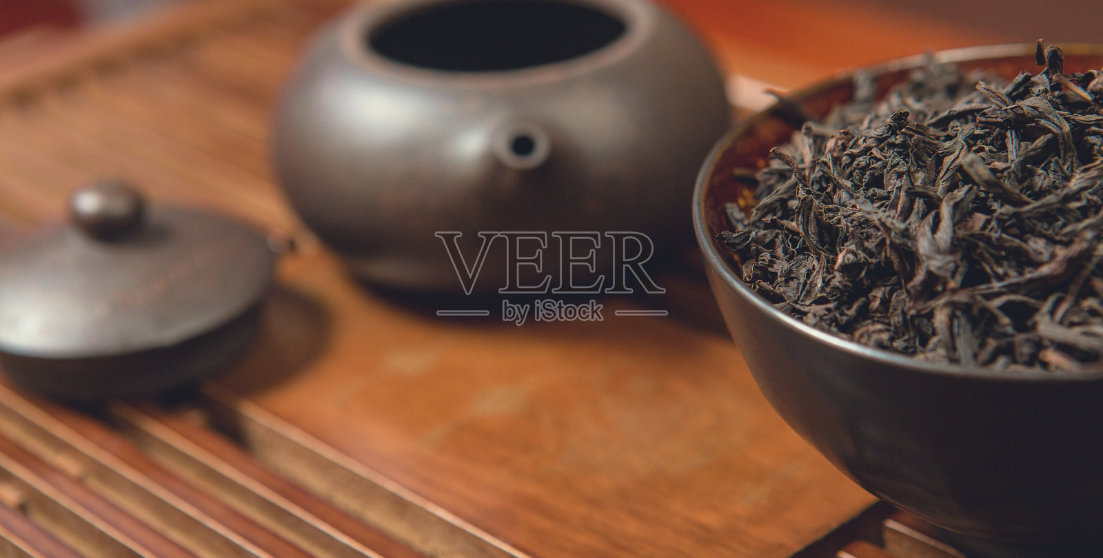 中国茶道。陶土制成的茶壶和木制背景的碗。照片摄影图片