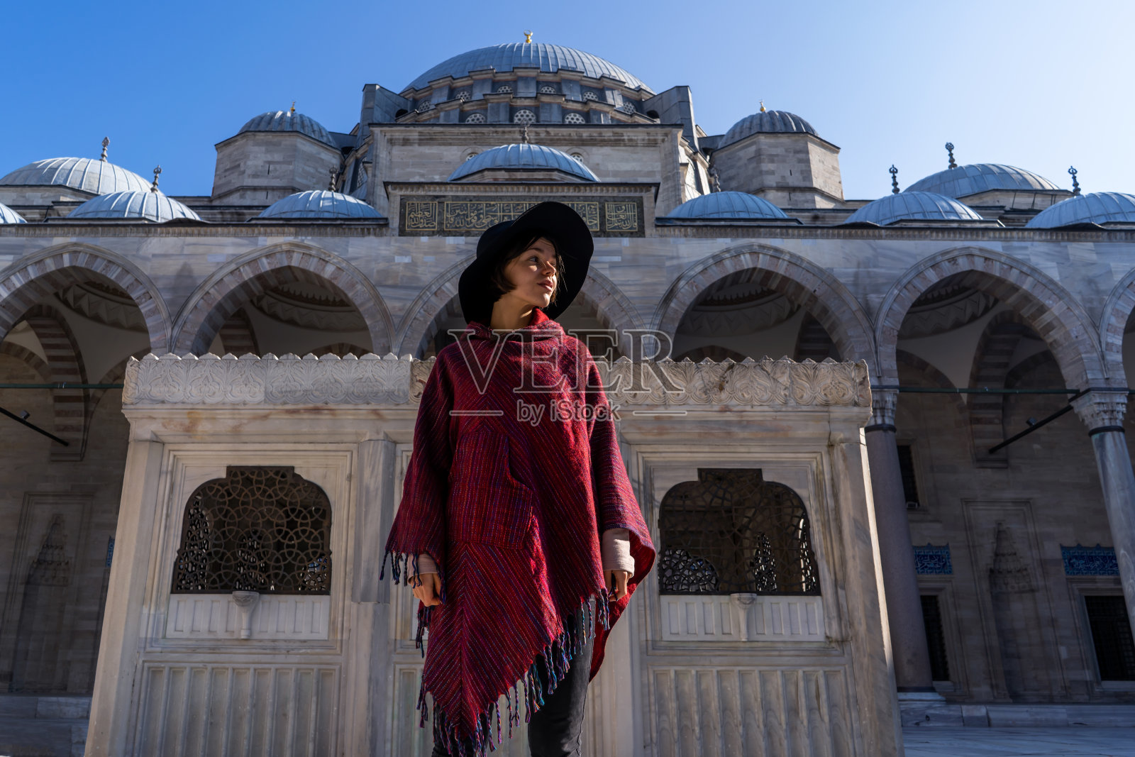 一个戴着黑色头巾的穆斯林女孩站在有图案的锻铁围栏后面。照片摄影图片