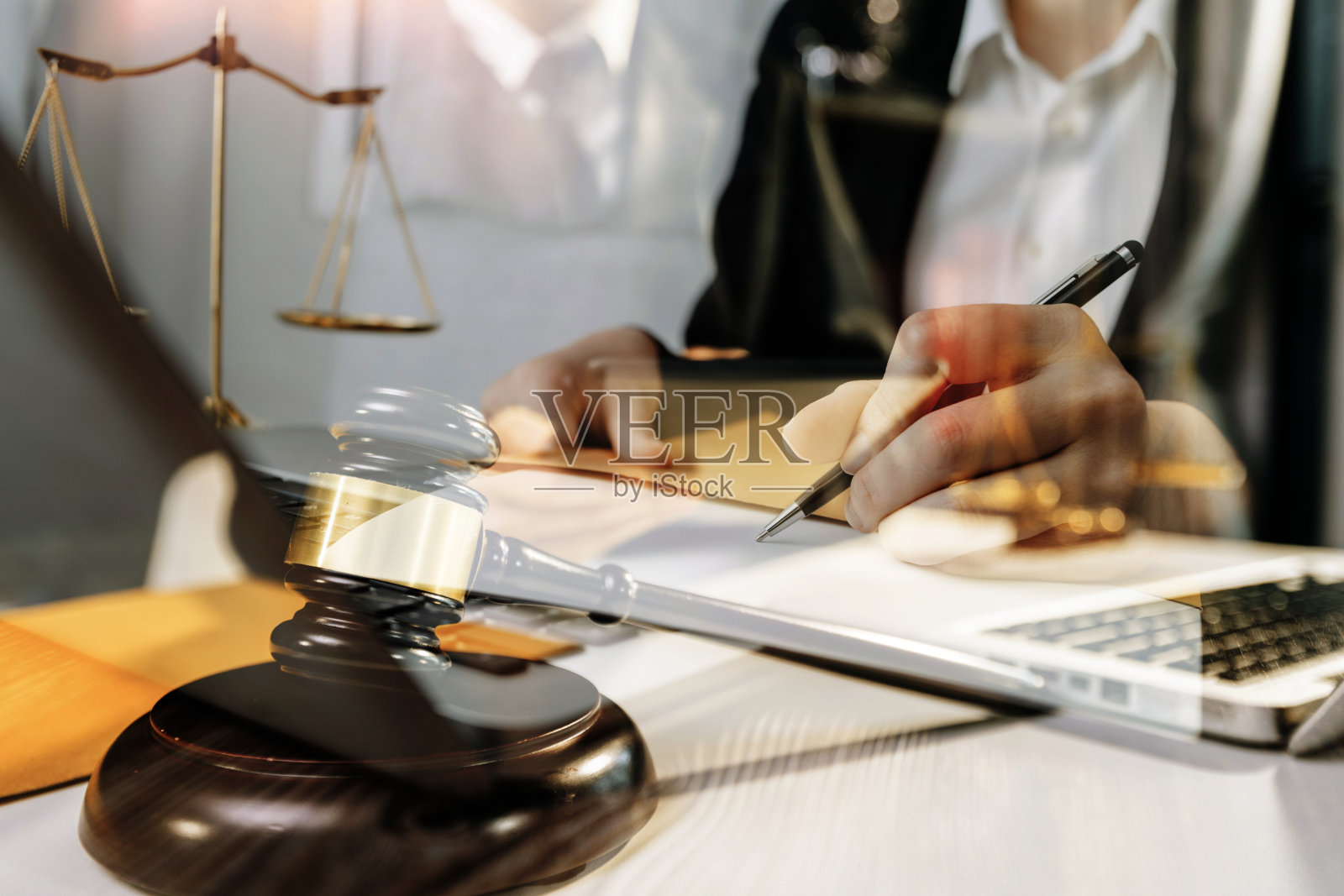 商务人士与律师在办公室讨论合同文件，桌面有黄铜天平。法律、法律服务、建议、公正和法律概念。照片摄影图片