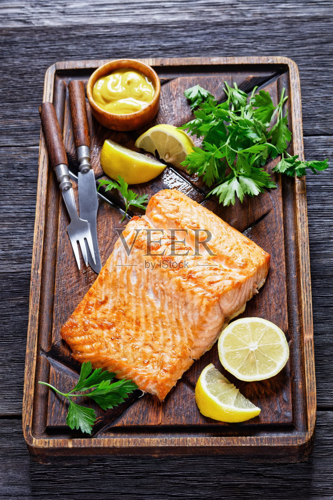 烤三文鱼片放在粗糙的木砧板上，配上芥末和柠檬照片摄影图片