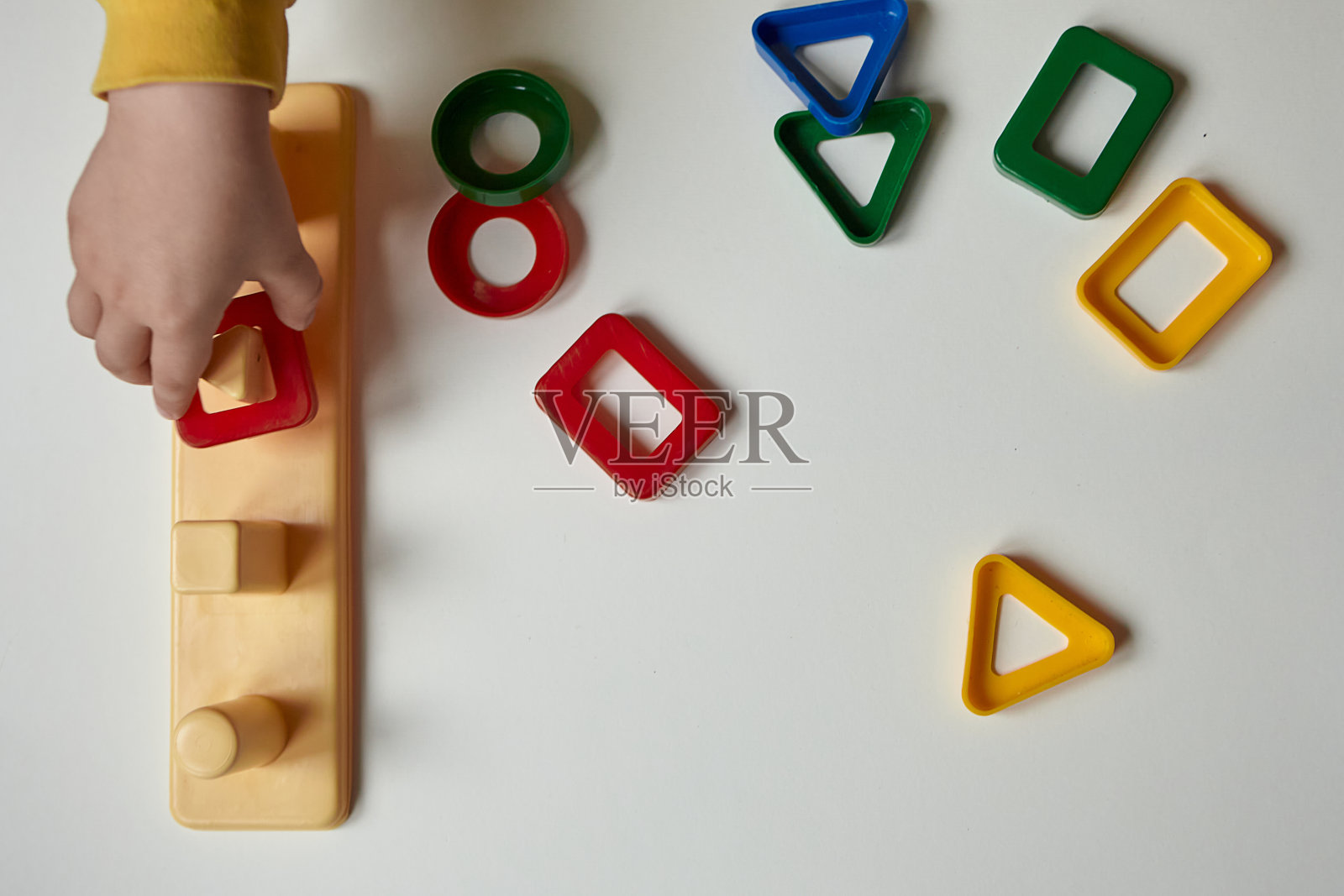 那个男孩正在他的房间里玩。有教育意义的游戏。学习形状和颜色。一个孩子在玩一个分类器。照片摄影图片