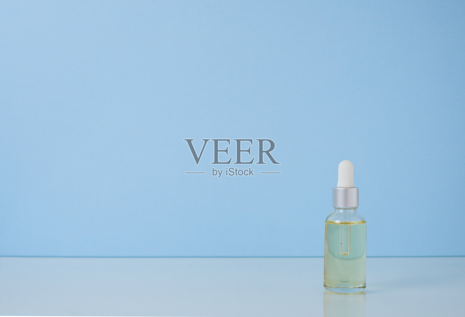 蓝色背景的玻璃瓶里的血清。香薰油，天然化妆品概念照片摄影图片