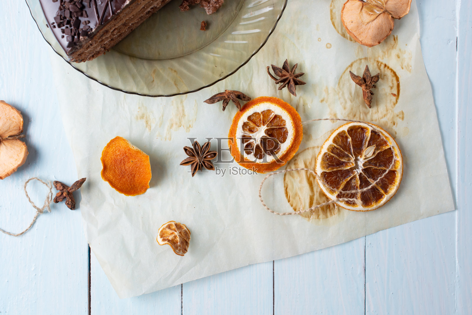 一片巧克力蛋糕，干燥的圆柠檬和苹果角和八角在蓝色的木头背景照片摄影图片