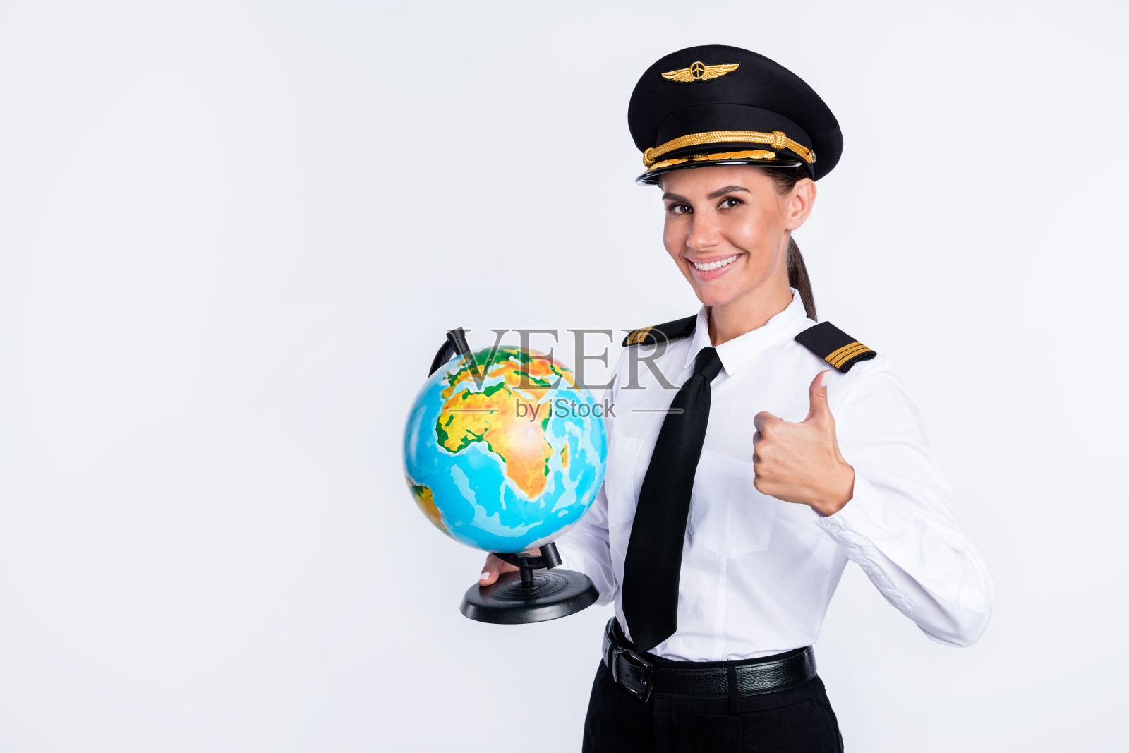 美丽开朗的飞行员女孩的肖像在双手地球灯显示拇指广告孤立在白色背景照片摄影图片