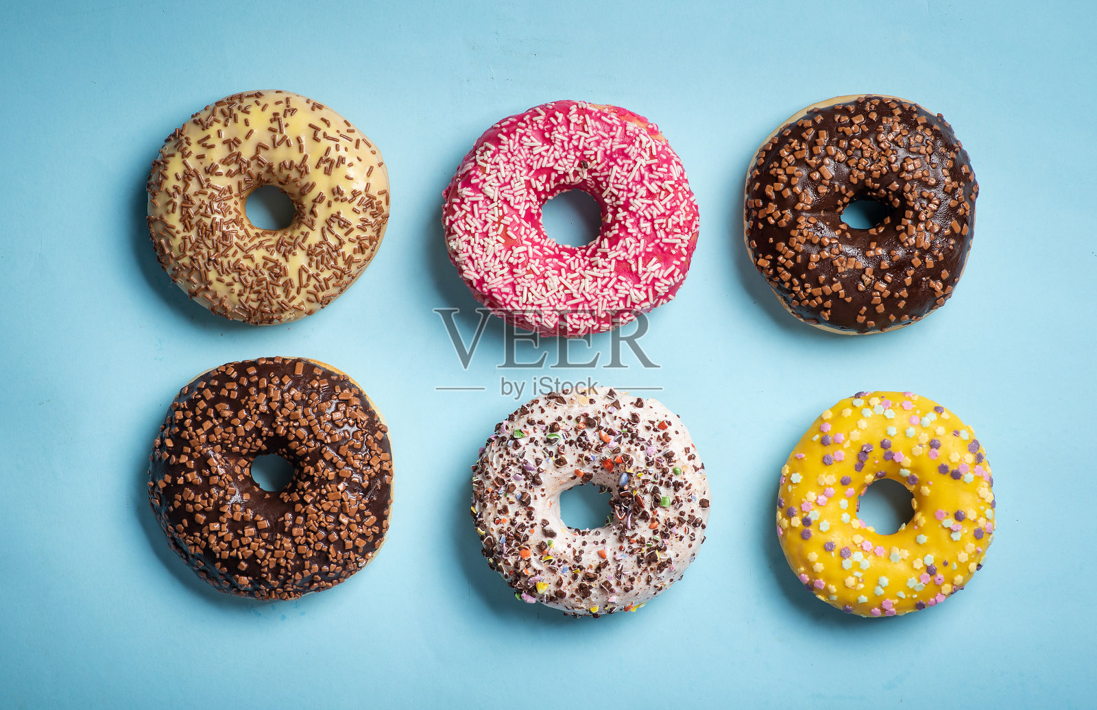 彩色巧克力覆盖的甜甜甜圈和甜蜜的点缀甜点在蓝色的背景照片摄影图片