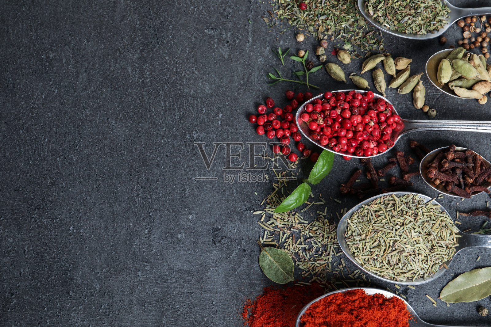 平铺构图用不同的天然香料和药草在黑色的桌子上，文字空间照片摄影图片